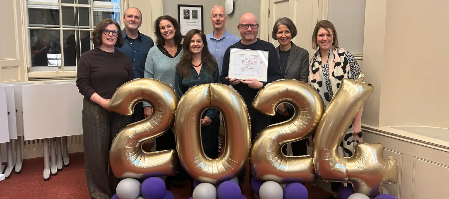 James Smith with colleagues standing in front of 2024 balloons at his leaving reception