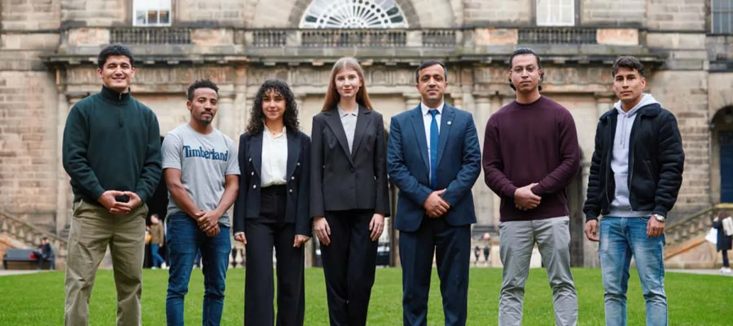 A group of seven professionals from Education Beyond Borders standing in front of the University's Old College.