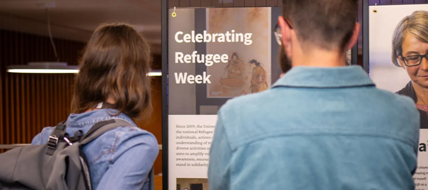 Two people looking at a display that says "Celebrating Refugee Week".