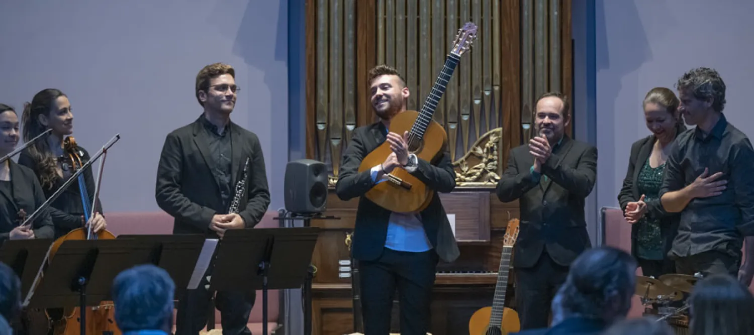 People holding instruments in an auditorium in front of an audience.