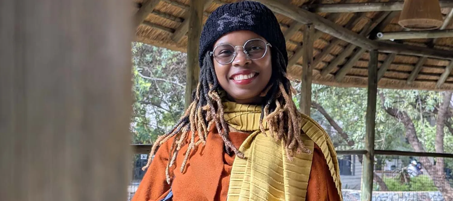 Headshot of Mwende Kasoyoki smiling at the camera in an orange jacket.