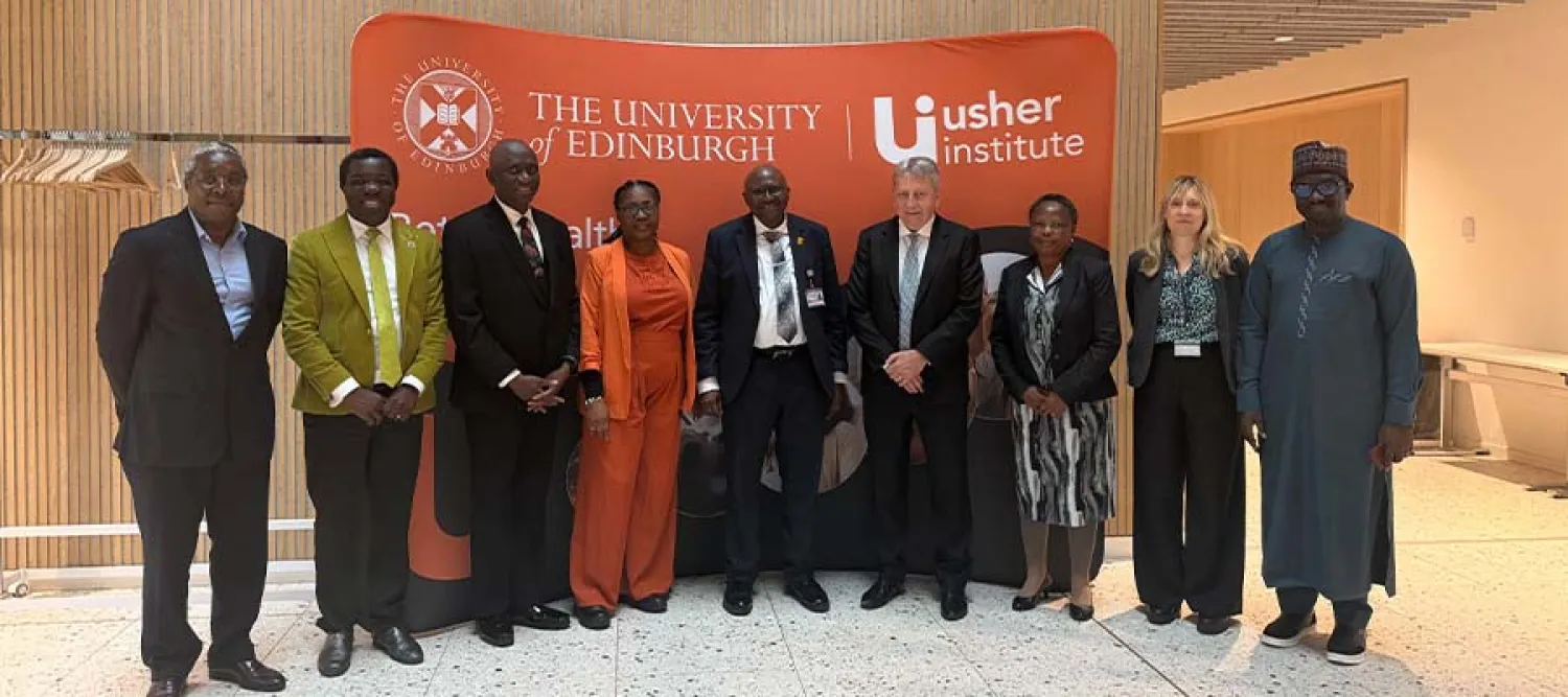 Nine people, including senior leaders from the Universities of Edinburgh and Ibadan, standing and smiling in front of an orange sign that reads "The University of Edinburgh" and "the Usher Institute".