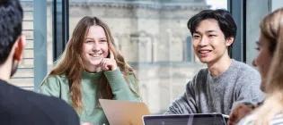 Students speaking and laughing around a table.