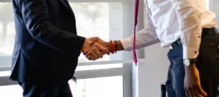 Two people in professional attire shaking hands.