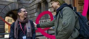 Two students speaking and laughing outside the University of Edinburgh.