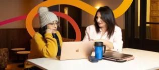 Two students sitting at a desk studying with a laptop.
