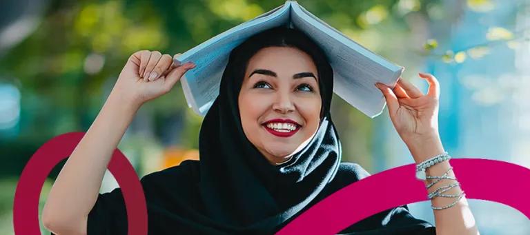 Smiling scholar holding book over her head