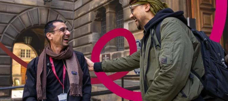 Two students speaking and laughing outside the University of Edinburgh.