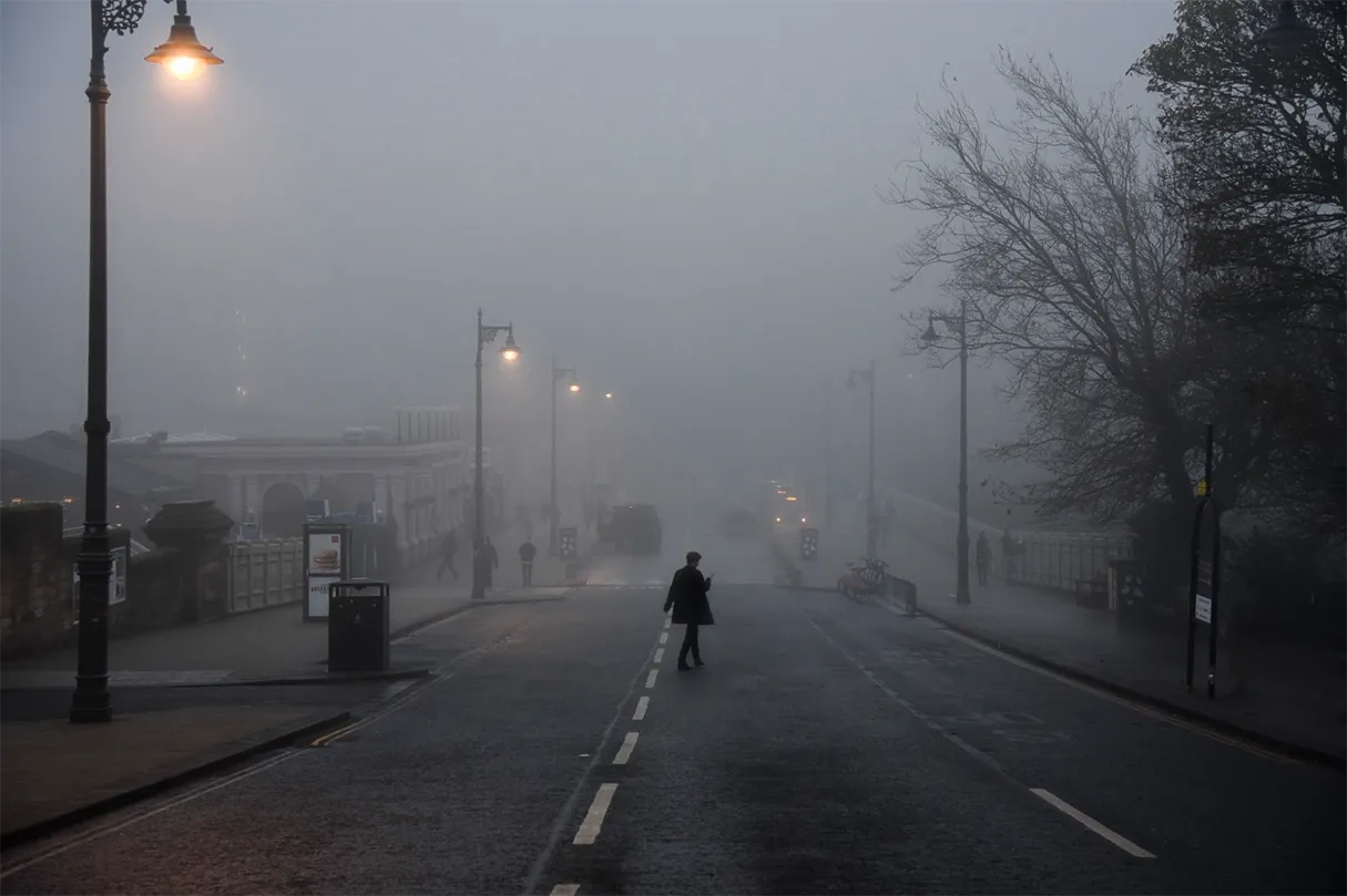 Waverley Bridge, Edinburgh, in the fog with a solitary figure crossing the street.