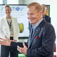 Bill Nelson smiling and talking to a group. Other people in professional attire can be seen in the background.
