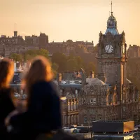 Two people looking out at a clocktower with Edinburgh Castle visible in the background.