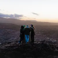 People huddled in a group overlooking Edinburgh city at sunset.
