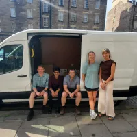 Staff from Edinburgh Global beside a white van with boxes loaded inside the side door