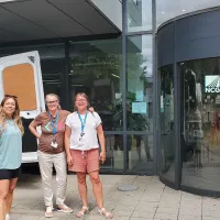 Three women standing beside white van outside Newcastle College University