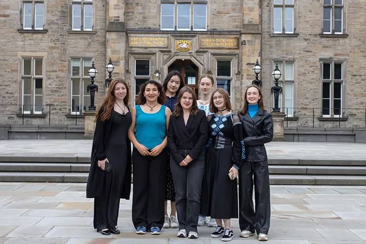 Seven students standing in front of the Edinburgh Futures Institute.