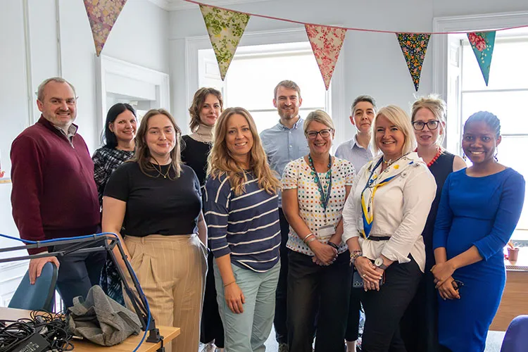 A group of adults standing in a room smiling at the camera.