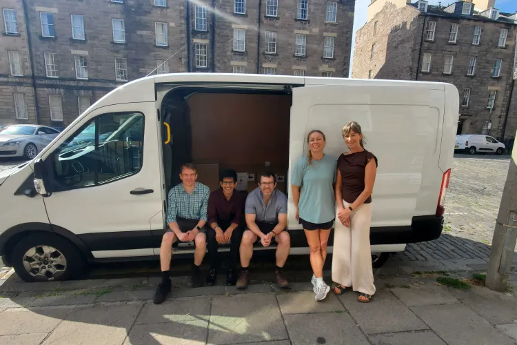 Staff from Edinburgh Global beside a white van with boxes loaded inside the side door