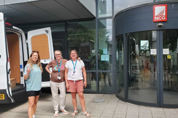 Three women standing beside white van outside Newcastle College University