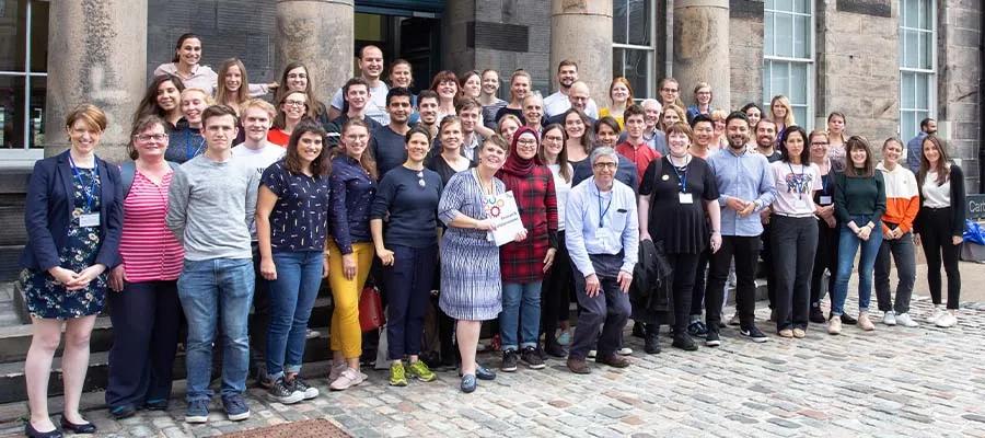 A large group of professionals standing outside ECCI at the University of Edinburgh.