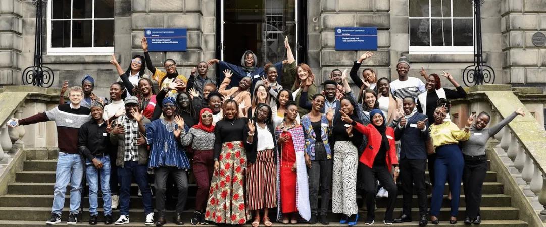 large group of MCF staff and scholars posing happily at Old College