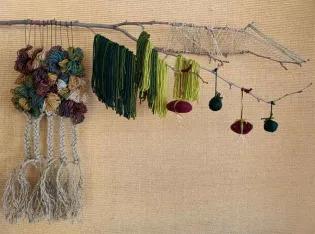 A mixed-medium artwork, made from a branch with wool and string wrapped around it.