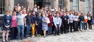 A large group of professionals standing outside ECCI at the University of Edinburgh.