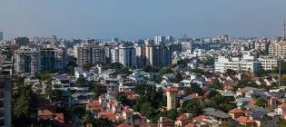 Skyline of Ahmedabad in India, including a mix of tall buildings and short houses against a blue sky.