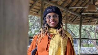 Headshot of Mwende Kasoyoki smiling at the camera in an orange jacket.