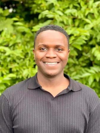 A headshot of Julian Mashingaidze smiling at the camera.